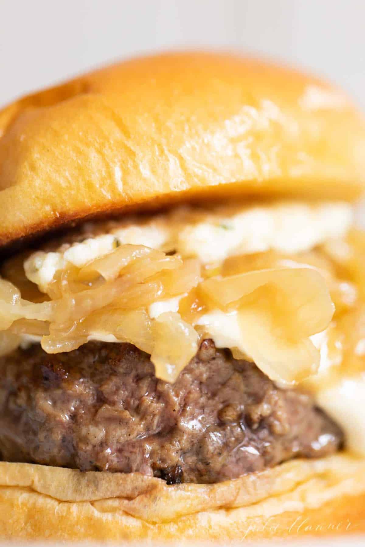 Close up of a gourmet burger with caramelized onions and boursin cheese.