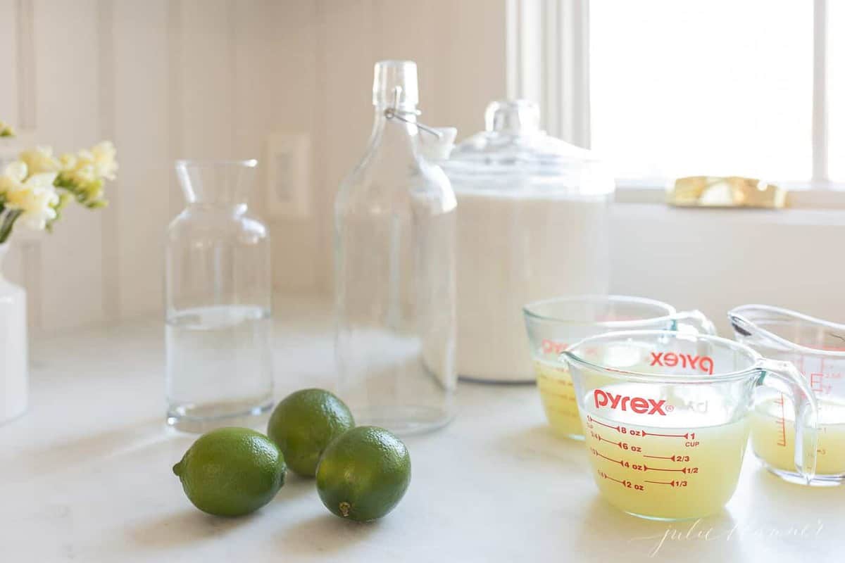 Glass bottles, limes, and fresh squeezed lime juice for a homemade margarita mix.