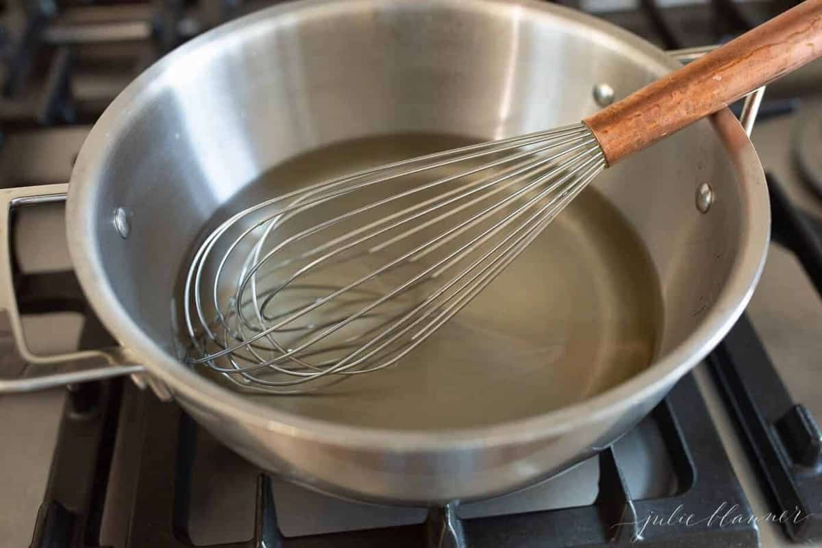 A stainless steel pan with a whisk inside, creating simple syrup for margarita mix.