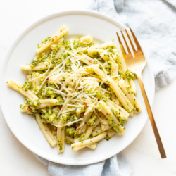 A white plate filled with broccoli pasta, blue napkin behind.