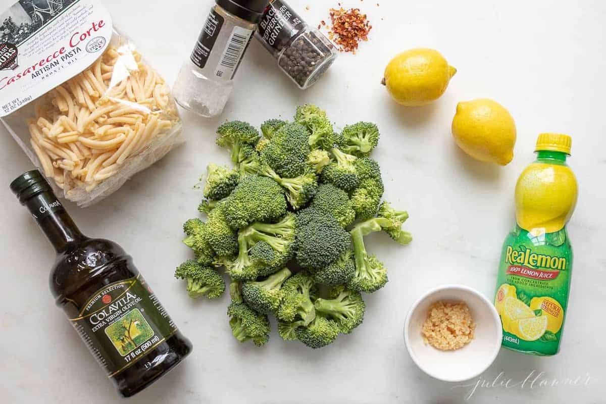 A white surface with ingredients for broccoli pasta