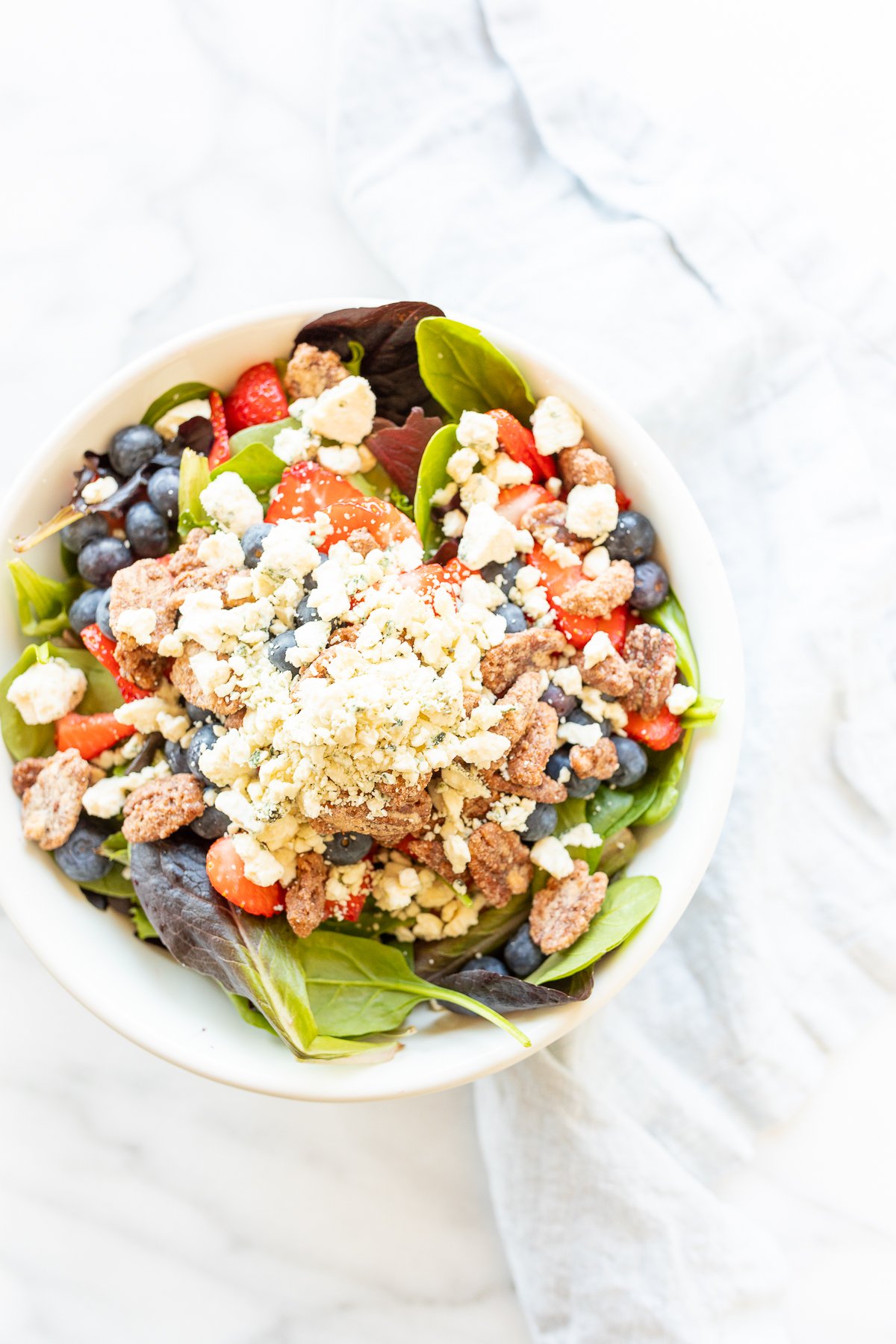 A bowl of salad with berries, meat, and Champagne Vinaigrette.