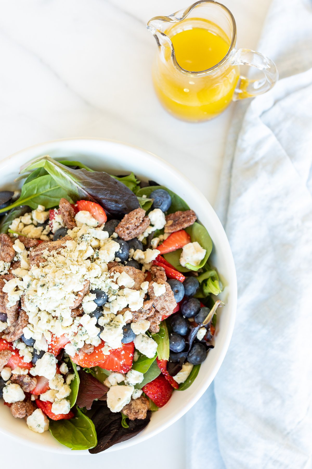 A salad bowl with blueberries, strawberries and goat cheese dressed in champagne vinaigrette.