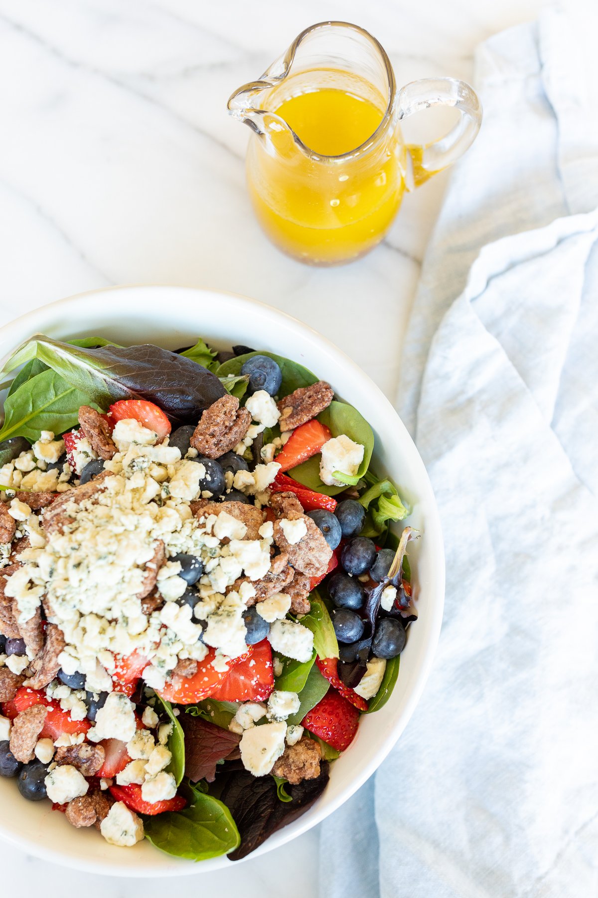 A bowl of salad with blueberries and blue cheese.