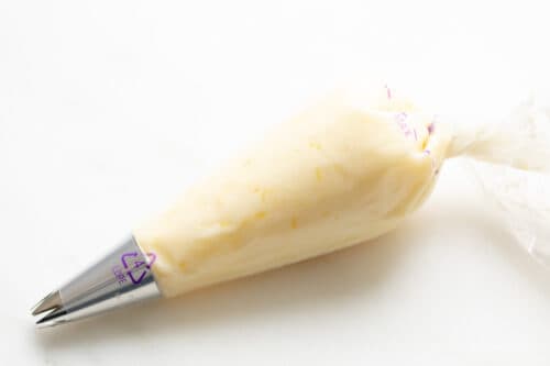 Piping bag of lemon frosting for cookies, on a marble surface