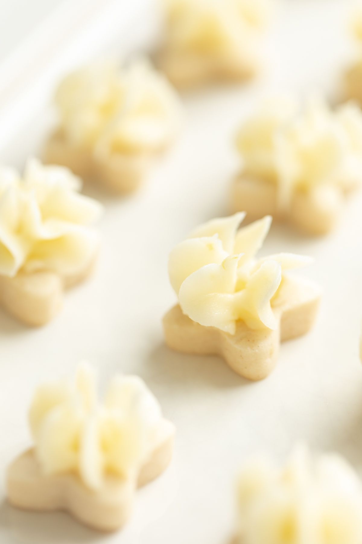 Tiny frosted lemon shortbread cookies on a white platter.