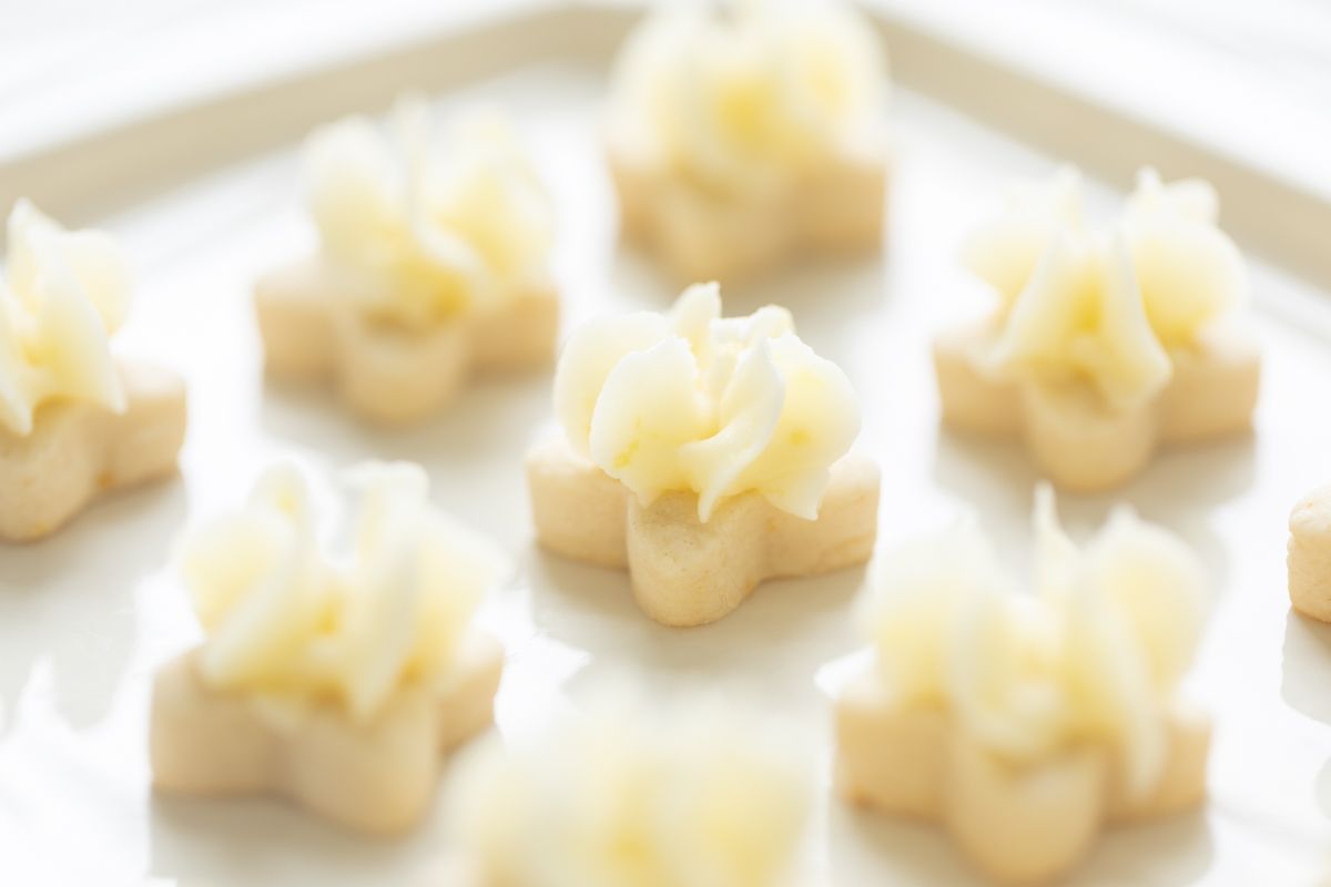 Tiny frosted lemon shortbread cookies on a white platter.