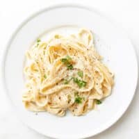 White plate full of fettuccine alfredo.