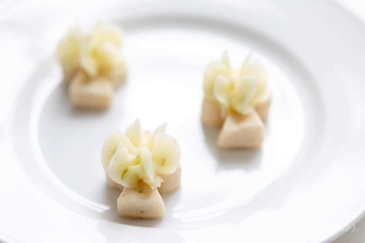 A white plate with cute little lime cookies topped with lime frosting.