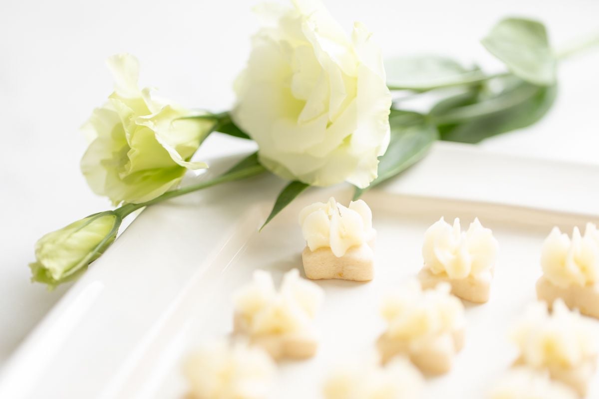 Tiny frosted lemon shortbread cookies on a white platter.