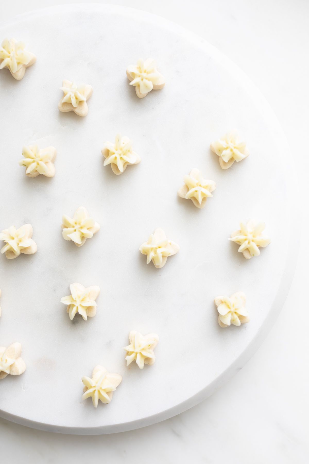 A white platter full of frosted key lime cookies.