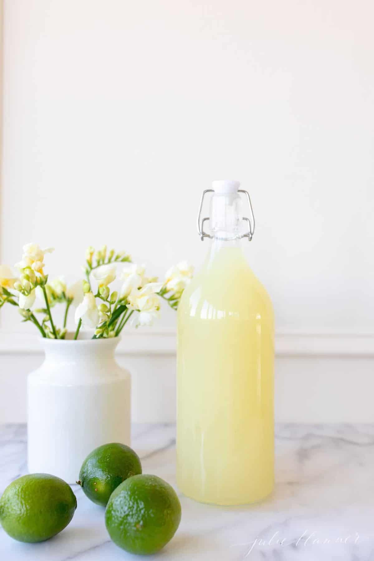 White kitchen background, glass carafe full of homemade margarita mix.