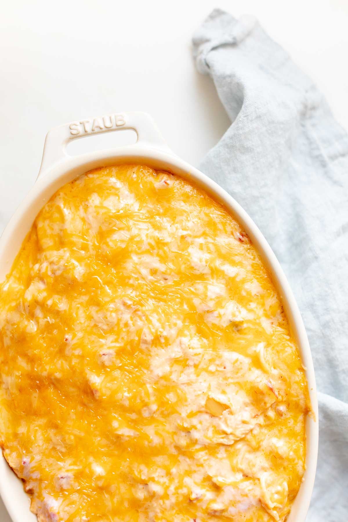 Mexican spaghetti in an oval baking dish, topped with shredded cheese