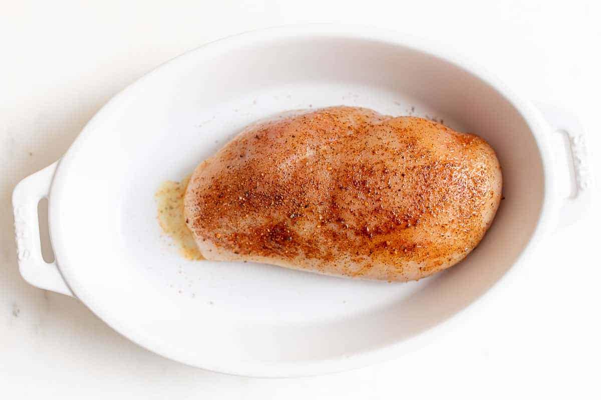 chicken coated with olive oil and seasoning in white dish