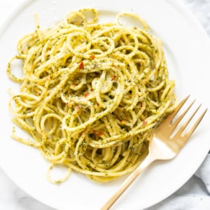 Pesto pasta recipe on a white plate with a fork.