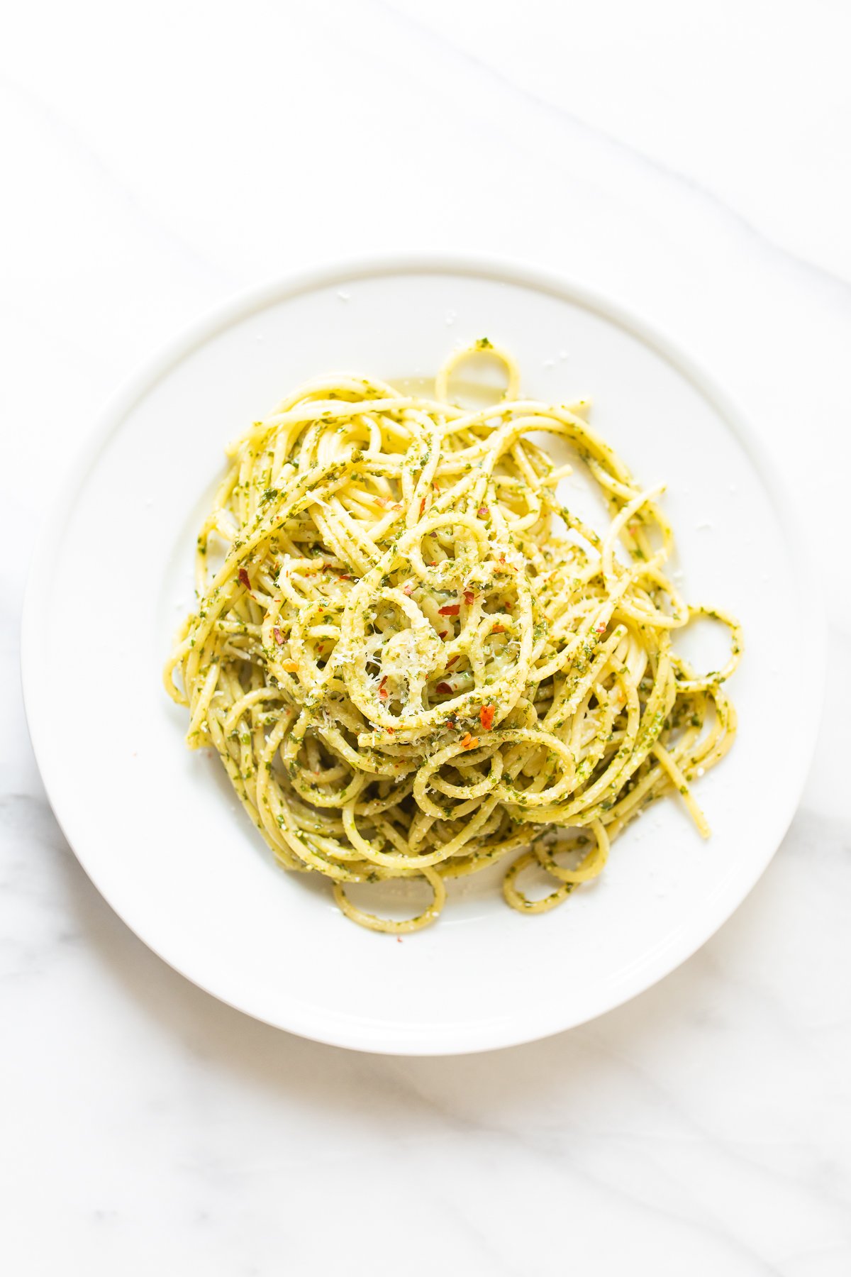 Delicious pesto pasta on a white plate.