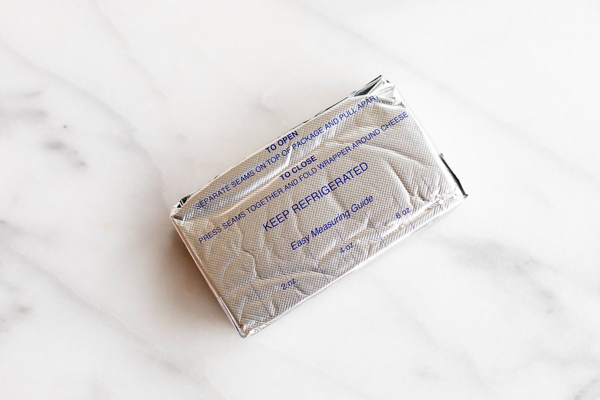 A vacuum-sealed cream cheese package on a marble surface.