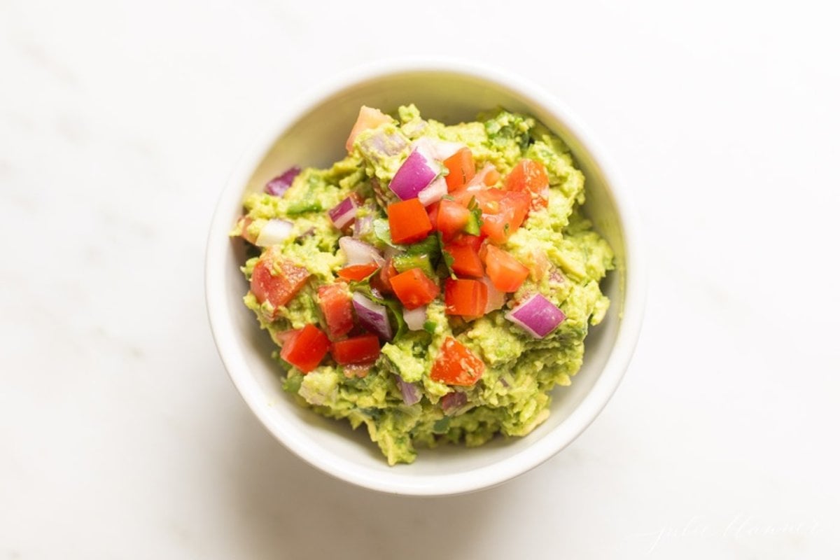 A white bowl full of fresh homemade guacamole.