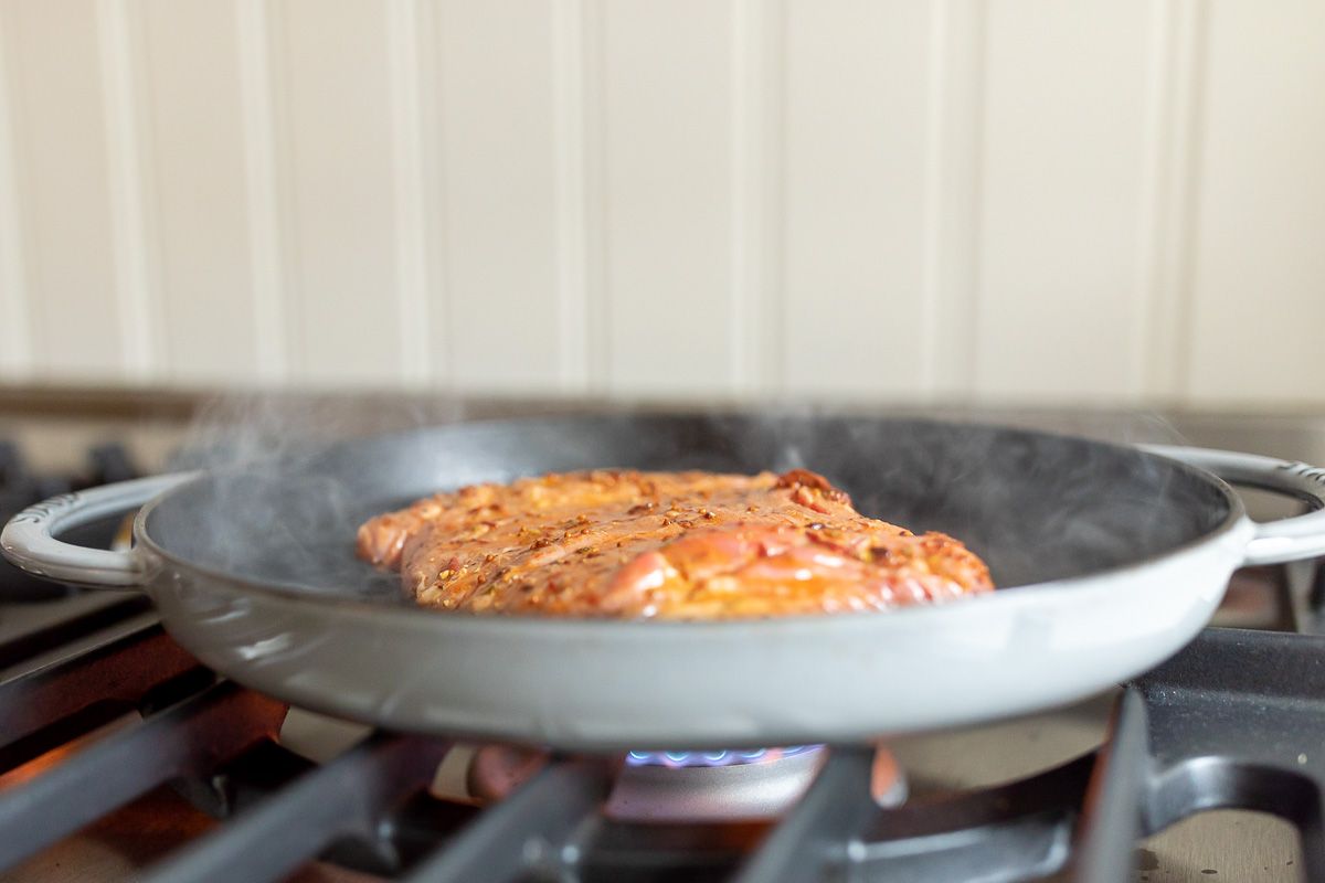 Carne asada recipe cooking in a cast iron pan on a stove top