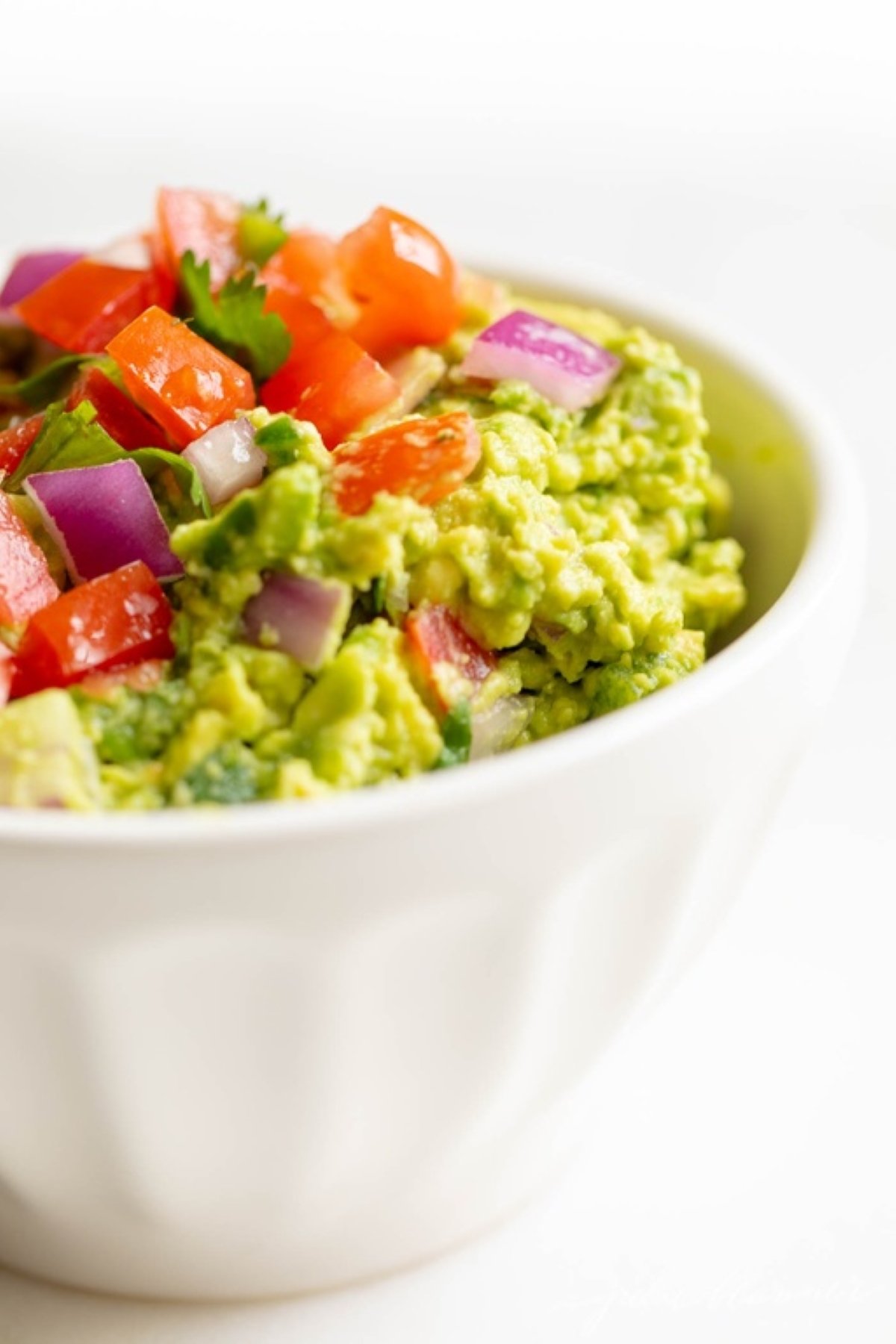 A white bowl full of fresh homemade guacamole.