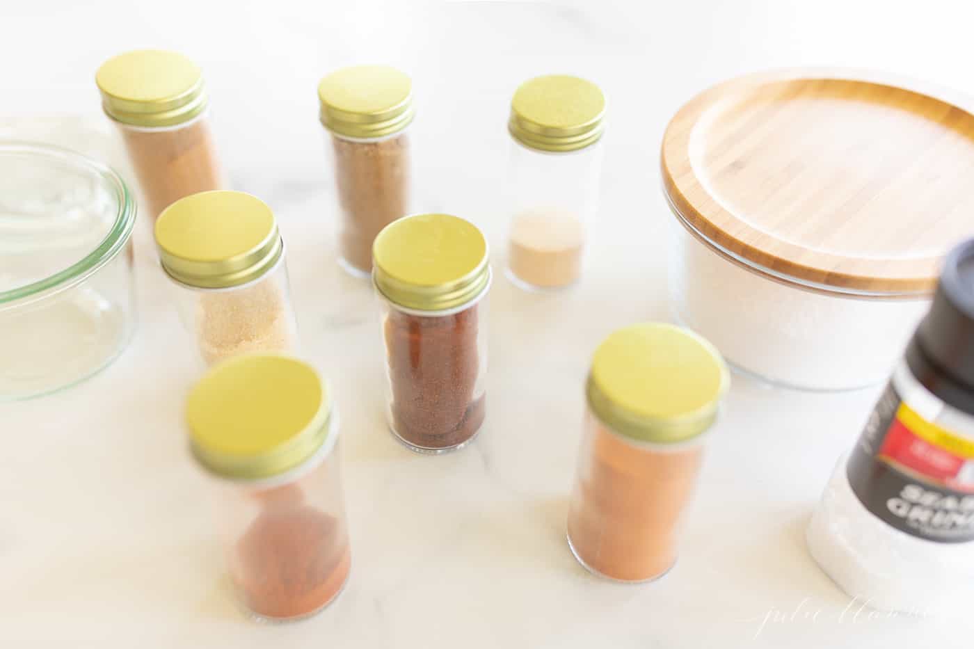 Various spices in small glass containers on a countertop.