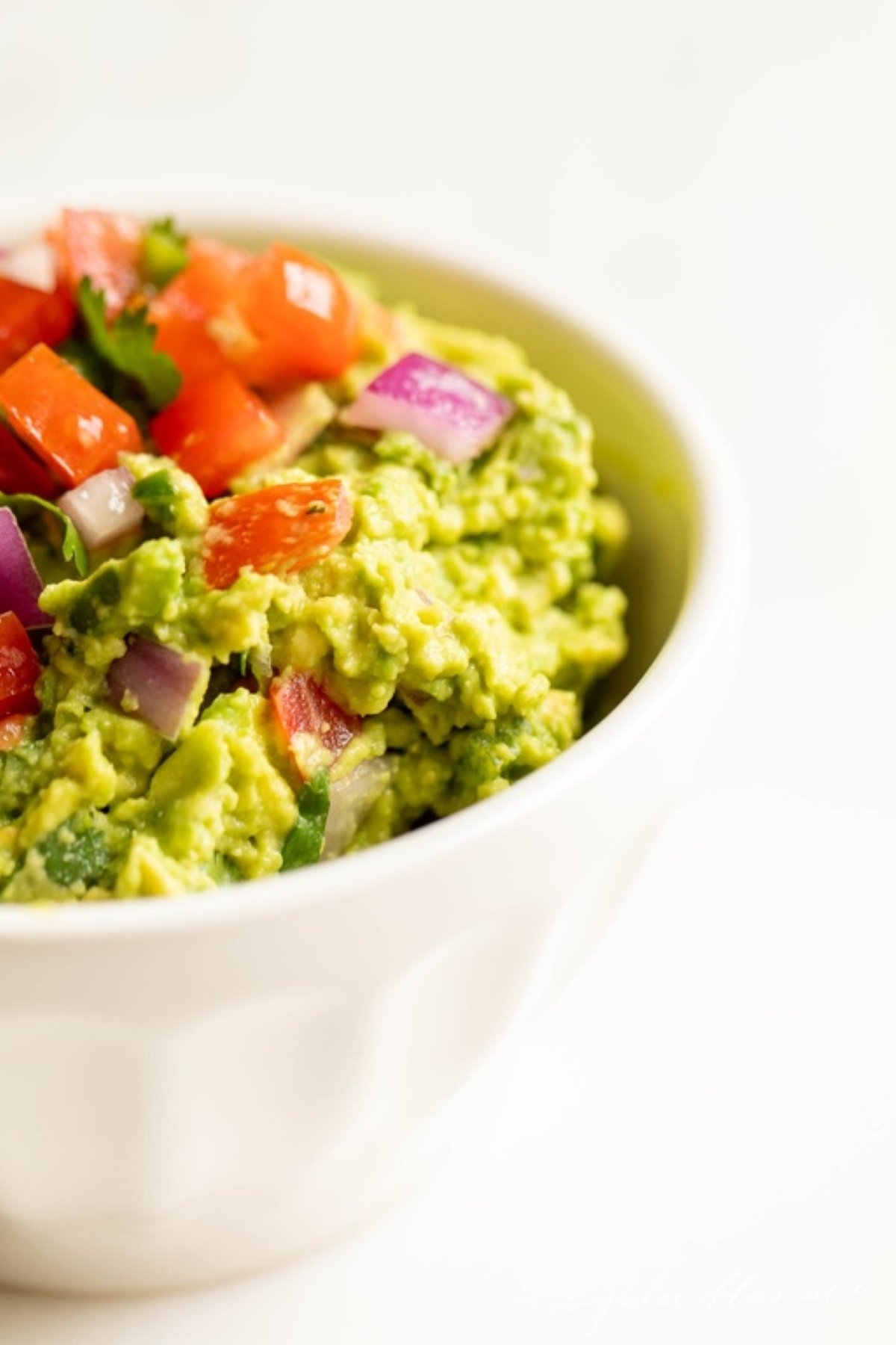 A white bowl full of fresh homemade guacamole.