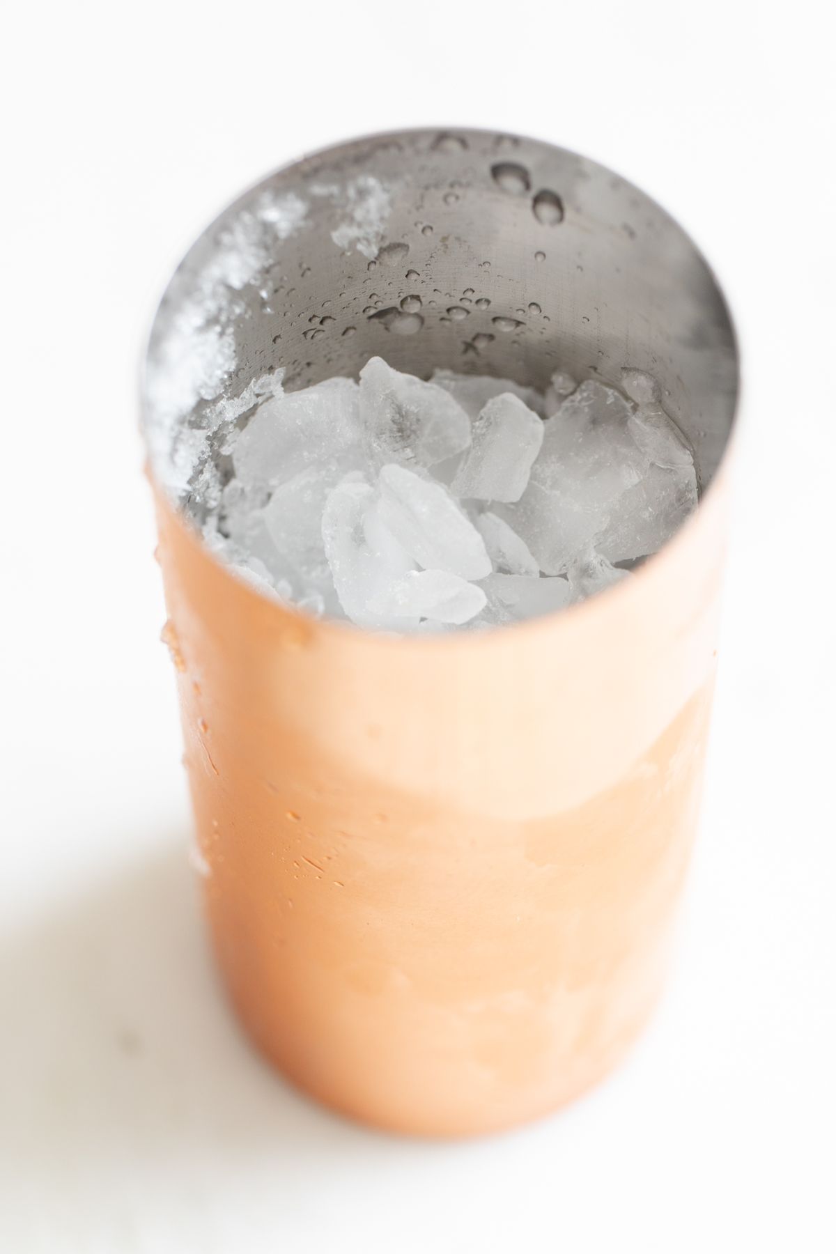 A copper cocktail shaker filled with crushed ice.