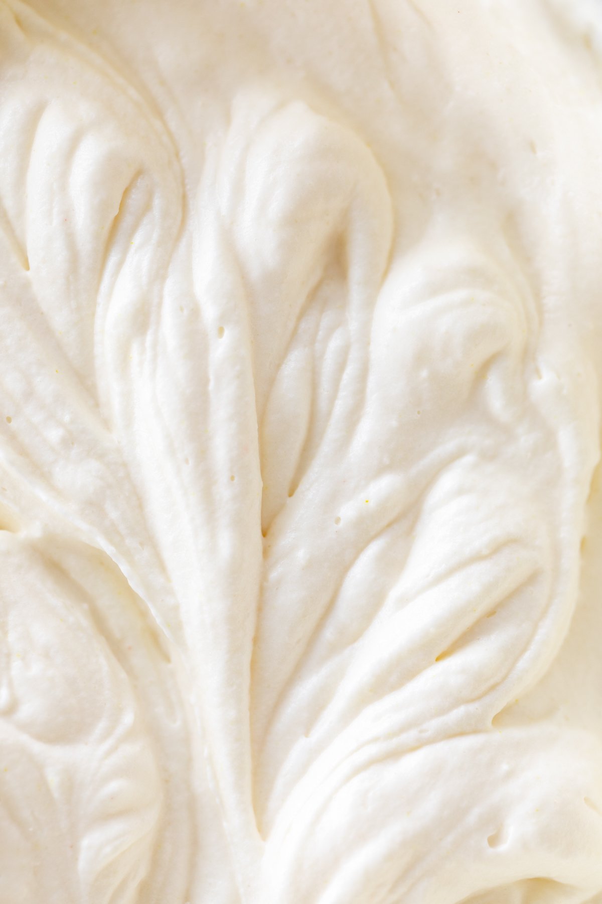 Condensed milk ice cream being whipped in the glass bowl of a stand mixer.