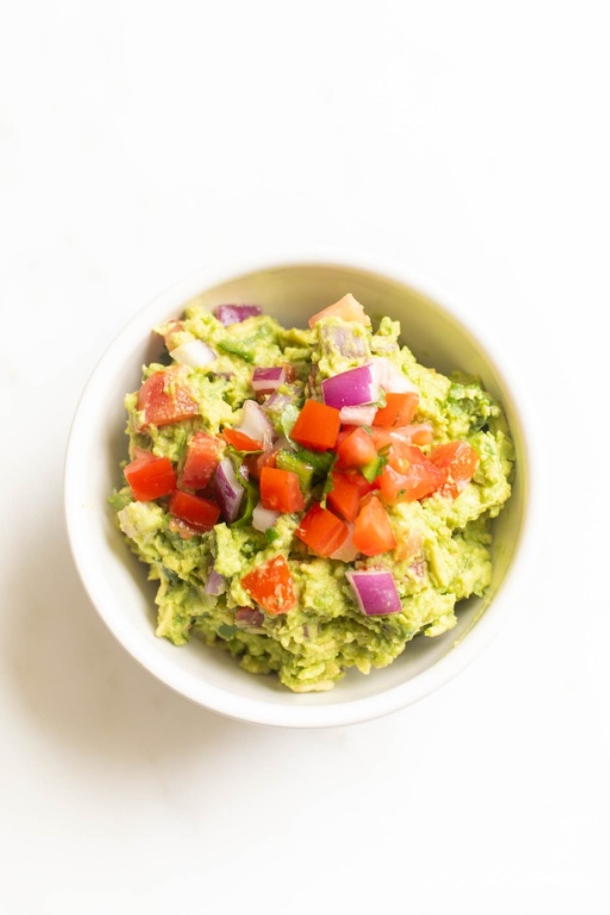 A white bowl full of fresh homemade guacamole.