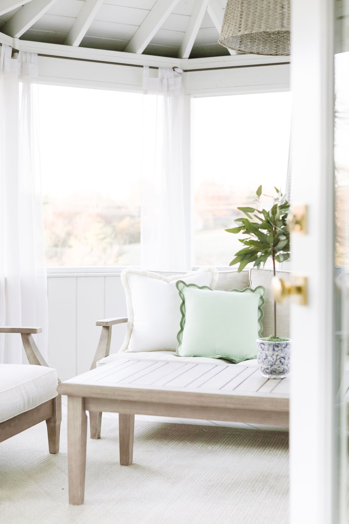 A white screened-in porch with white furniture, perfect for outdoor living design.