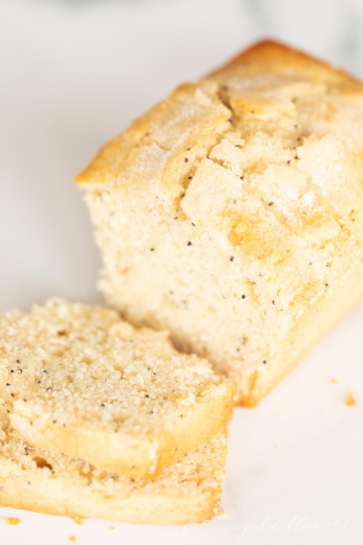 A poppy seed loaf of bread, sliced on a marble countertop.