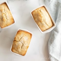 Small loaves of poppy seed bread on a white countertop.