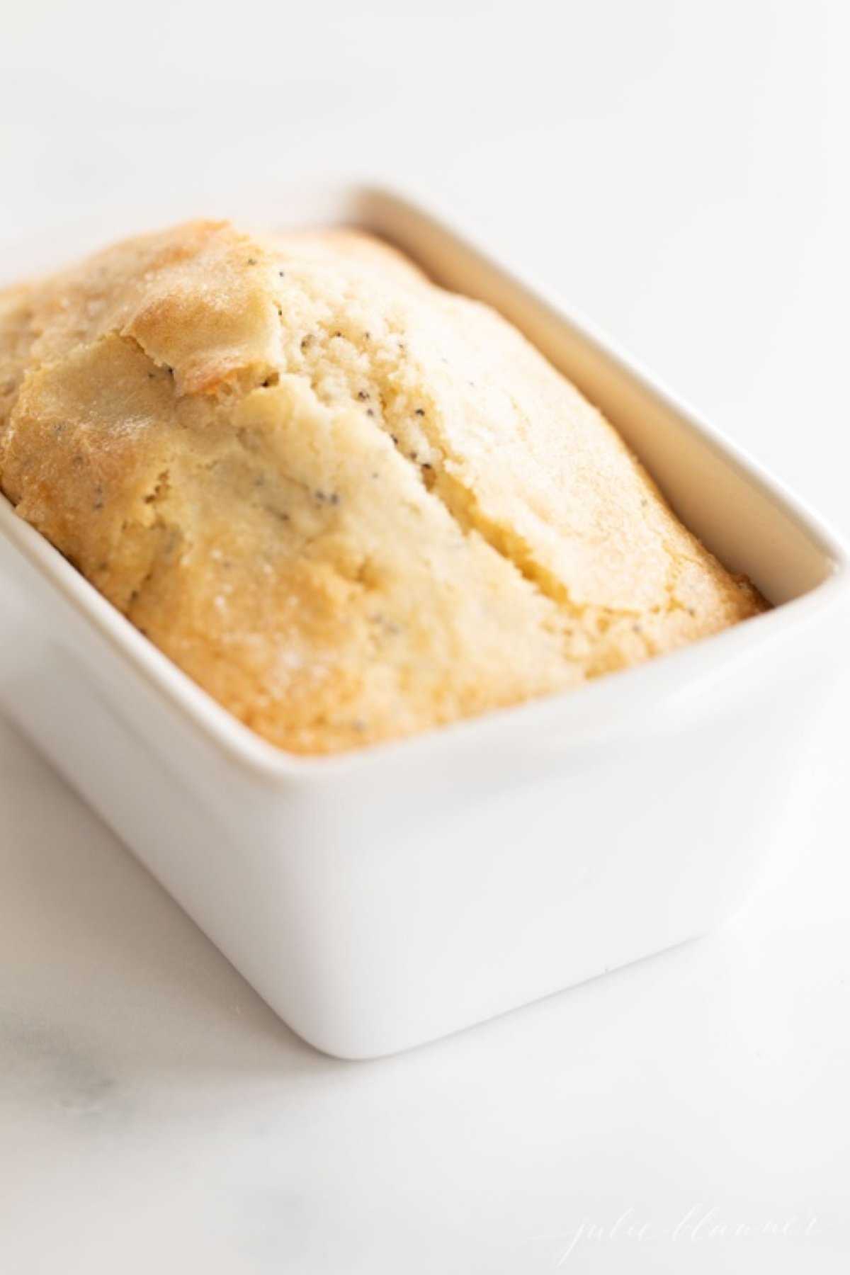 A small loaf of poppy seed bread on a marble countertop.