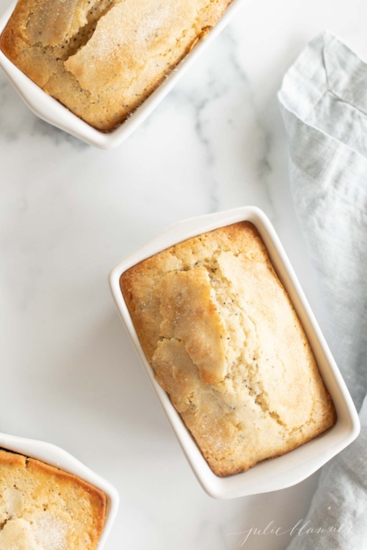 Small loaves of poppy seed bread on a white countertop.