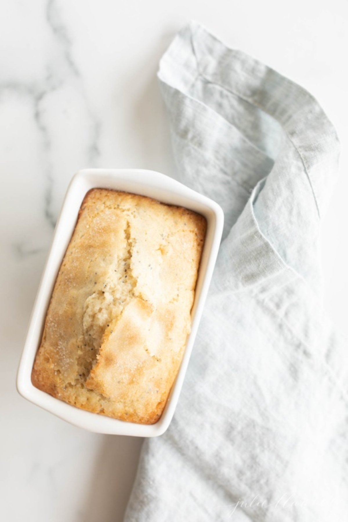 A small loaf of poppy seed bread on a marble countertop. 