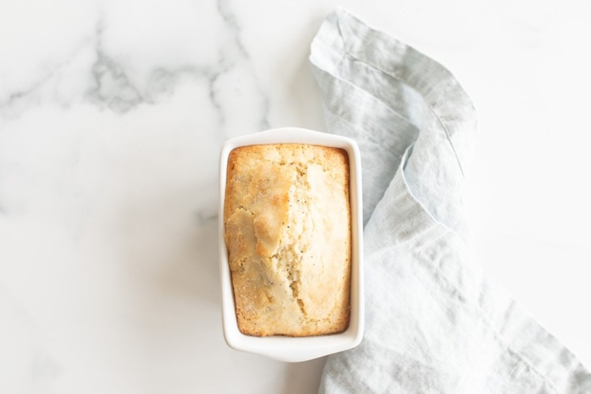 A small loaf of poppy seed bread on a marble countertop.