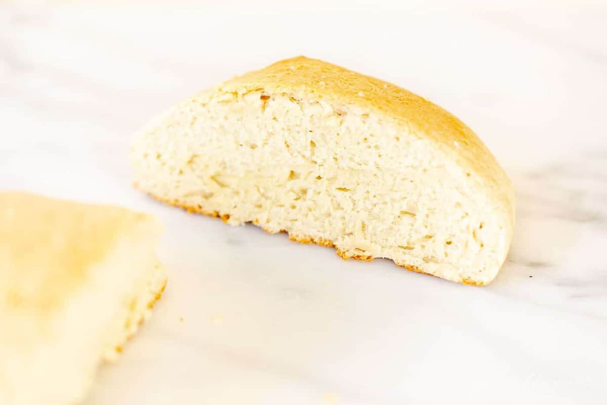 A marble surface with a loaf of homemade rosemary bread sliced in half.