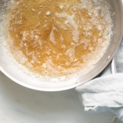 A silver pan with handle, warm browned butter inside, showing how to brown butter.