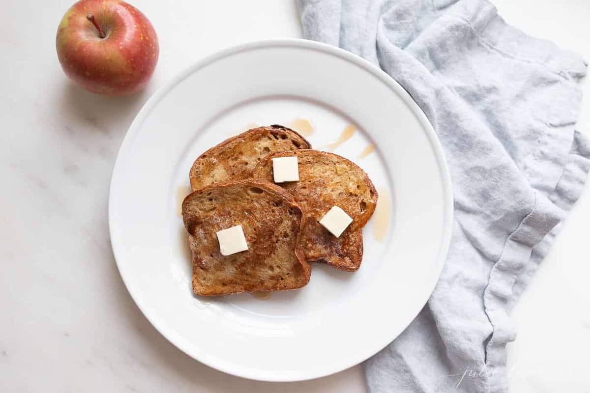 A white plate with slices of apple fritter french bread.