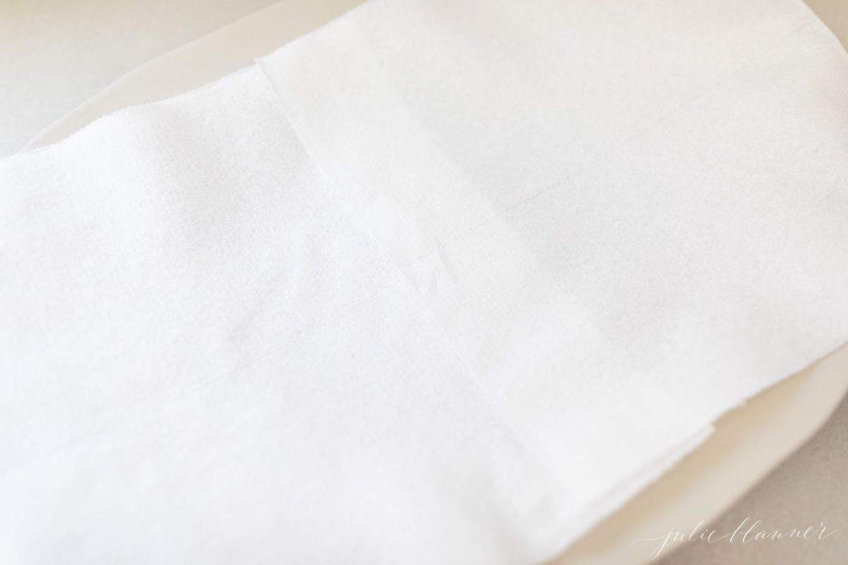 A white plate with a white paper towel on top in a lesson on how to make biscuit donuts.