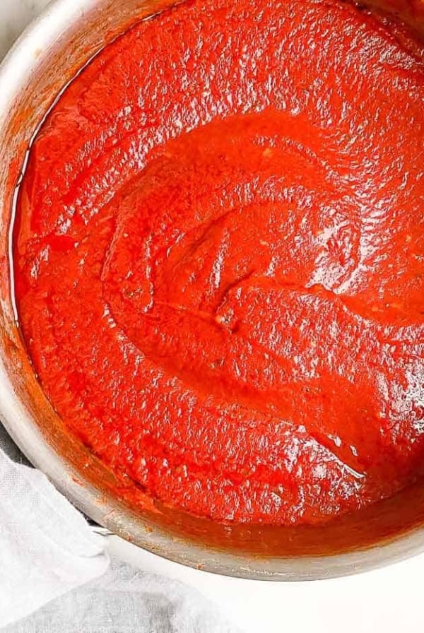A silver sauce pan filled with homemade pizza sauce.