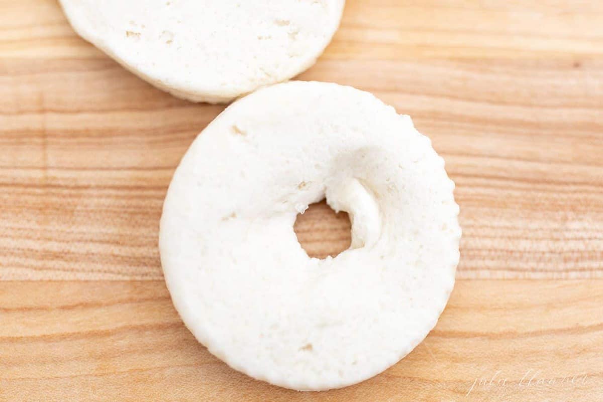 A wooden surface with raw biscuit dough ring, hole in the center.