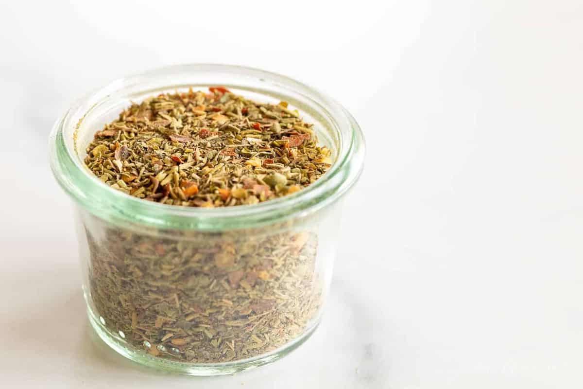 A clear glass jar of italian seasoning blend.