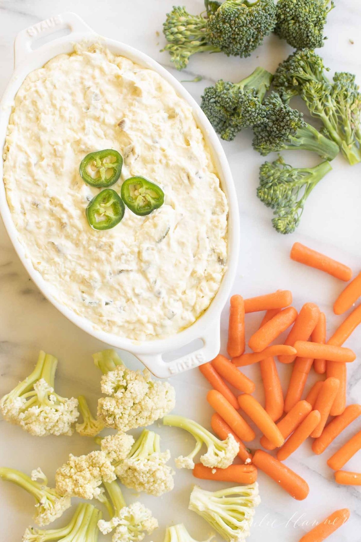 A creamy jalapeno dip surrounded by fresh vegetables for dipping.