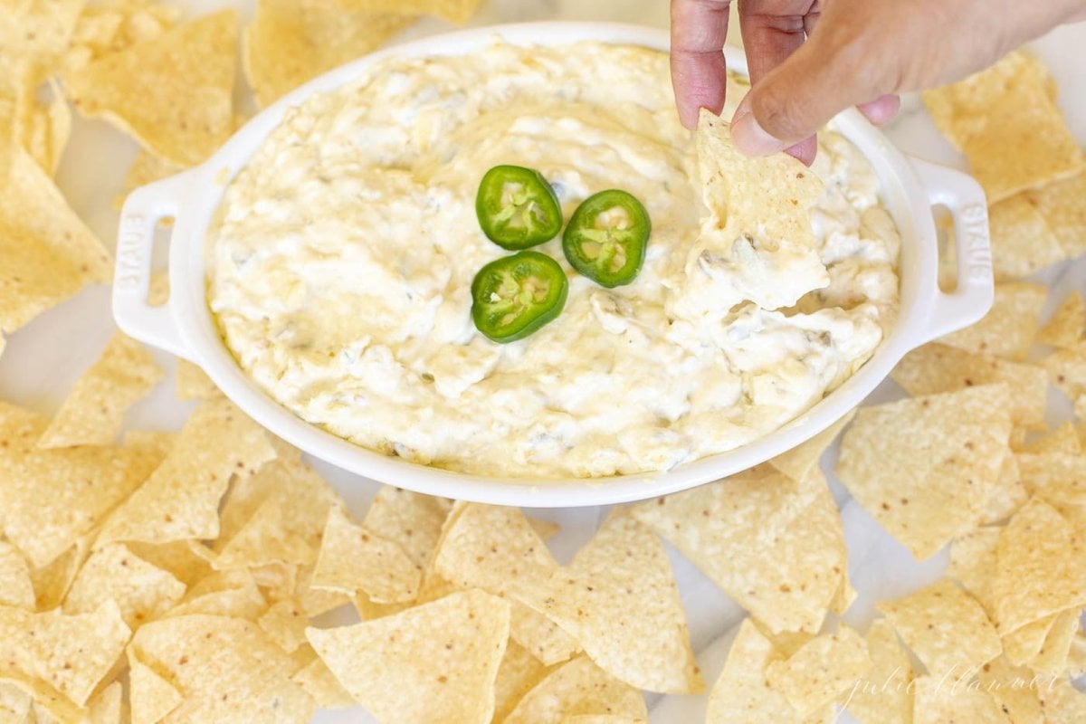 An oval serving dish full of jalapeno dip, surrounded by tortilla chips.