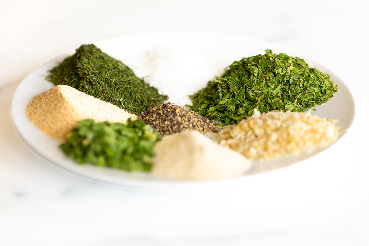 Seasonings and spices on a white plate for a homemade ranch seasoning recipe.