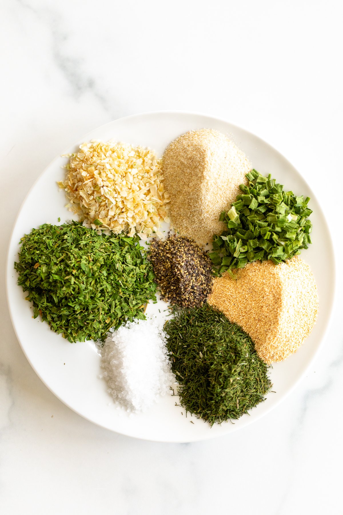 Seasonings and spices on a white plate for a homemade ranch seasoning recipe.