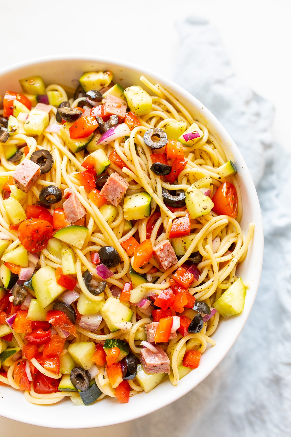 A white bowl full of cold spaghetti salad.