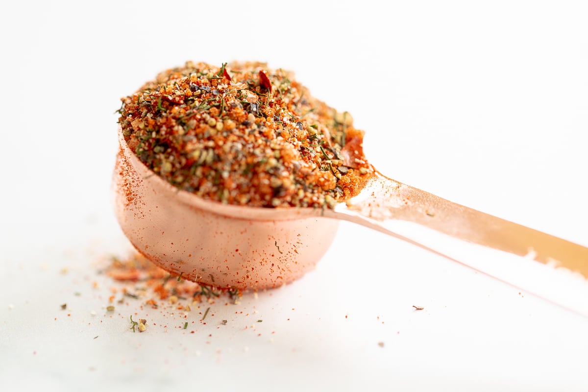 A spoon full of best steak seasoning on a white surface.