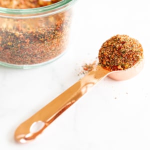 A jar of best steak seasoning with a spoon next to it.